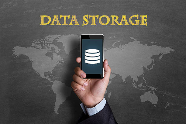Businessman hand's holding mobile phone with data storage icon and data storage text written on blackboard.